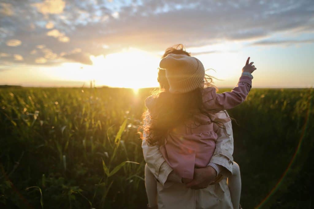 A person holding a small child in a corn field near Meridian Homes indianapolis rentals. pexels daria obymaha 1683975